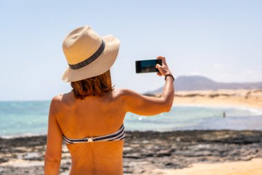 Genç bir turist, Kanarya Adaları, Fuerteventura 'daki Corralejo Doğal Parkı' nın kumsallarında fotoğraf çekiyor. İspanya