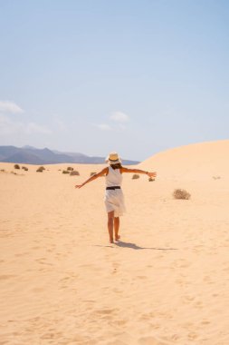 Kanarya Adaları, Fuerteventura 'daki Corralejo Doğal Parkı' nın kumullarında yürüyen şapkalı genç bir turist. İspanya