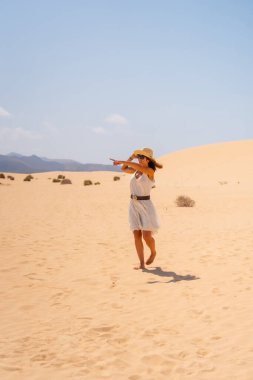 Kanarya Adaları, Fuerteventura 'daki Corralejo Doğal Parkı' nın kumullarında yürüyen şapkalı genç bir turist. İspanya