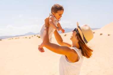 Genç anne, oğluyla birlikte Kanarya Adaları, Fuerteventura 'daki Corralejo Doğal Parkı' nın kumullarında oynuyor. İspanya