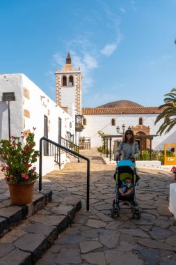 Betancuria 'nın beyaz kilisesinin yanında yürüyen genç bir anne Fuerteventura, Kanarya Adaları' nın batı kıyısında. İspanya