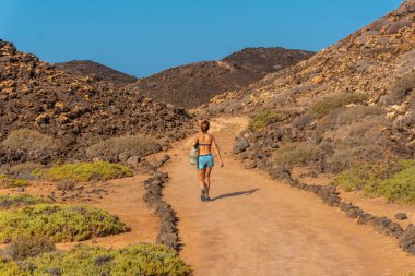 Lobos Adası 'nın kuzeyinde, Kanarya Adaları, Fuerteventura Adası' nın kuzey kıyısında, mavi bikinili genç bir kadın. İspanya