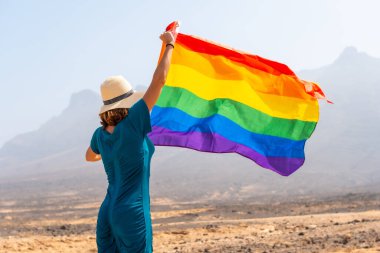 Lgbt sembolü, yeşil elbiseli bir lezbiyen ve çölde gökkuşağı bayrağı olan beyaz bir şapka.