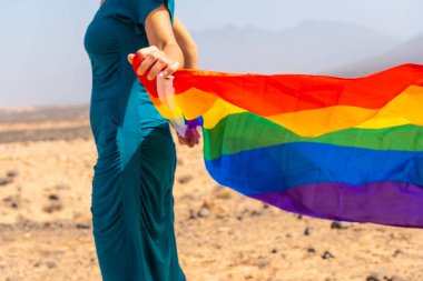 Lgbt sembolü, yeşil elbiseli tanınmayan bir lezbiyen ve deniz kenarında gökkuşağı bayrağı olan beyaz bir şapka.