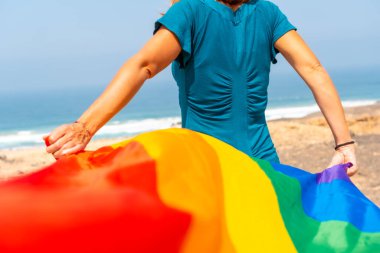 Lgbt sembolü, deniz kenarında bayrak sallayan, arkadan tanınmayan bir lezbiyen.