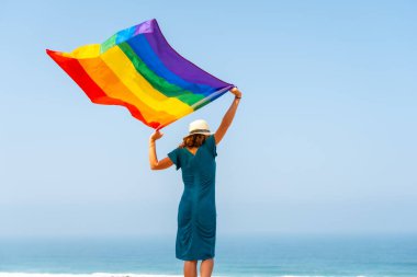 Lgbt sembolü, arkasından bayrak sallayan tanınmayan bir lezbiyen ve arka planda mavi gökyüzü