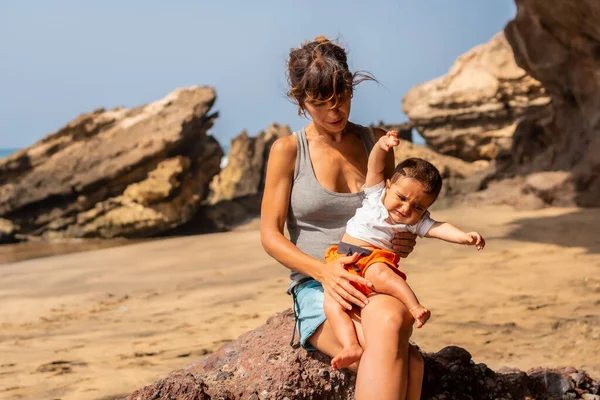 Playa de Garcey, Fuerteventura, Kanarya Adaları 'nın batı kıyısında ağlayan bebeğiyle birlikte genç bir annenin portresi. İspanya