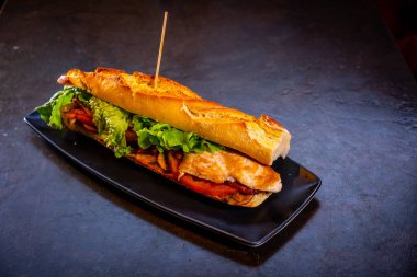 Siyah arka planda tavuklu vejetaryen sandviç, beyaz tabakta.