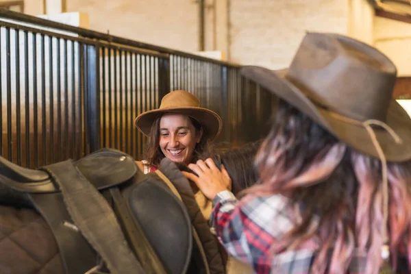 馬に乗る準備をしている2人のカウガールの女性安定した 南部のウサの帽子とジーンズ 垂直写真 — ストック写真