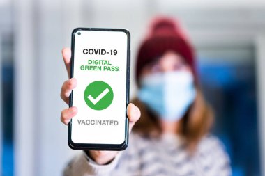 Covid-19 'un yeşil geçiş kartı, bir kadın sağlık pasaportlu bir cep telefonu gösteriyor. Barlara, restoranlara veya gece hayatına girmek için aşı sertifikası, koronavirüs