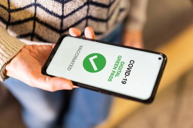 Covid-19 'un yeşil kartı, bir kadının detayları sağlık pasaportlu bir cep telefonu gösteriyor. Normal bir hayat sürmek için aşı belgesi