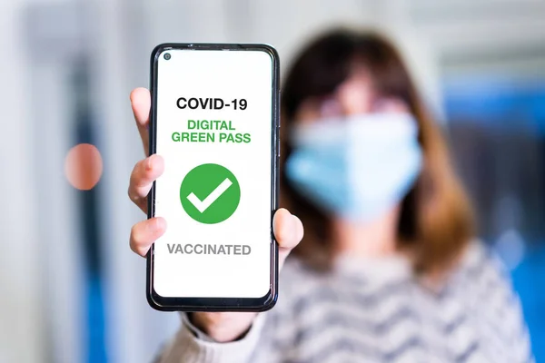 Covid-19 'un yeşil geçiş kartı, bir kadın sağlık pasaportlu bir cep telefonu gösteriyor. Barlara, restoranlara veya gece hayatına girmek için aşı sertifikası, koronavirüs