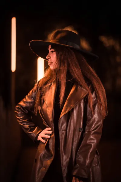 在公园里的人造照明下 一个晚上戴着帽子摆出姿势的女孩 冬夜时尚 — 图库照片