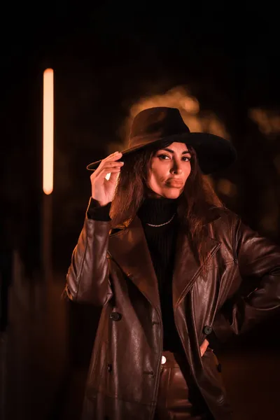 在公园里的人造照明下 一个晚上戴着帽子摆出姿势的女孩 冬夜时尚 — 图库照片