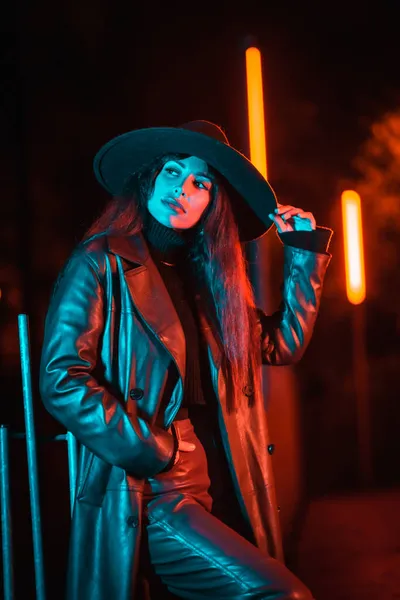 一个白种人的黑发女孩 晚上戴着帽子 在公园里被蓝光照亮 冬夜时尚与生活方式 纵向照片 — 图库照片