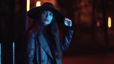 Parkta, mavi ışıkla aydınlatılmış, gece vakti şapkalı, beyaz esmer bir kız. Geceleri kış modası ve yaşam tarzı