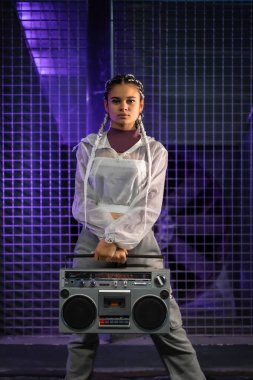 Beyaz örgülü genç bir kız, arka planda müzik çalar, mor ışıklar, 80 'ler tarzı, eski fotoğrafçılık, dikey fotoğraf