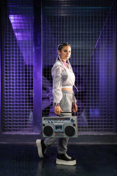 Young girl with white braids with a boombox on an urban background, purple lights, 80s style, retro photography