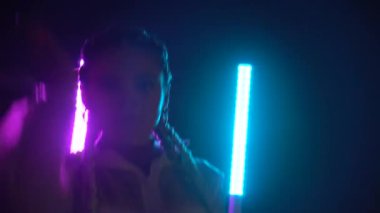Neon ışıklarıyla dans eden tuzak ya da rap dansçısı, mavi ve kırmızı ışıklarla dans eden, kameraya bakan 4K