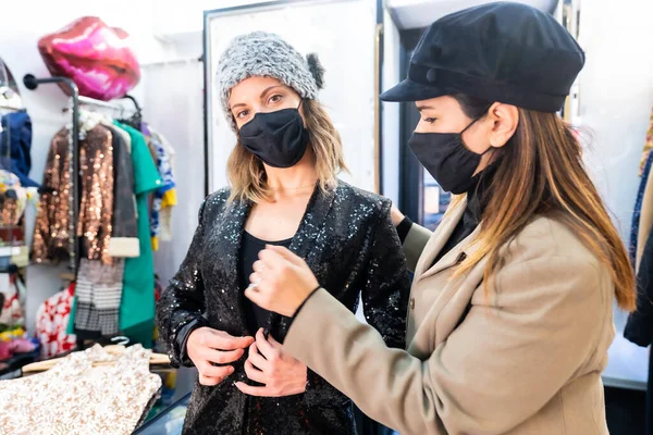 在一家奢侈品服装店工作的员工和戴口罩的客户 应对考利德19型流感大流行的安全措施 — 图库照片