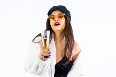 Siyah şapkalı genç Latin kız, yeni yıl arifesini beyaz bir arka planda kutluyor. Mankene meydan okuyorum. Bir kadeh şampanya.