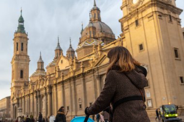 Gün batımında Zaragoza şehrindeki Plaza del Pilar 'ı ziyaret eden genç bir kadın, Aragon. İspanya