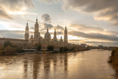 Aragon 'un Zaragoza kentindeki Ebro nehri üzerindeki Basilica De Nuestra Senora del Pilar' ın yanındaki taş köprüden gün batımı. İspanya