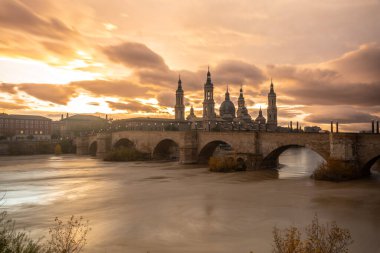 Aragon 'un Zaragoza kentindeki Ebro nehri üzerindeki Basilica De Nuestra Sinyora del Pilar' ın yanındaki Puente de Piedra 'da gün batımı. İspanya