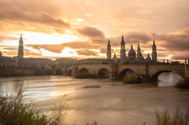 Aragon 'un Zaragoza kentindeki Ebro nehri üzerindeki Basilica De Nuestra Sinyora del Pilar' ın yanındaki Puente de Piedra 'da gün batımı. İspanya