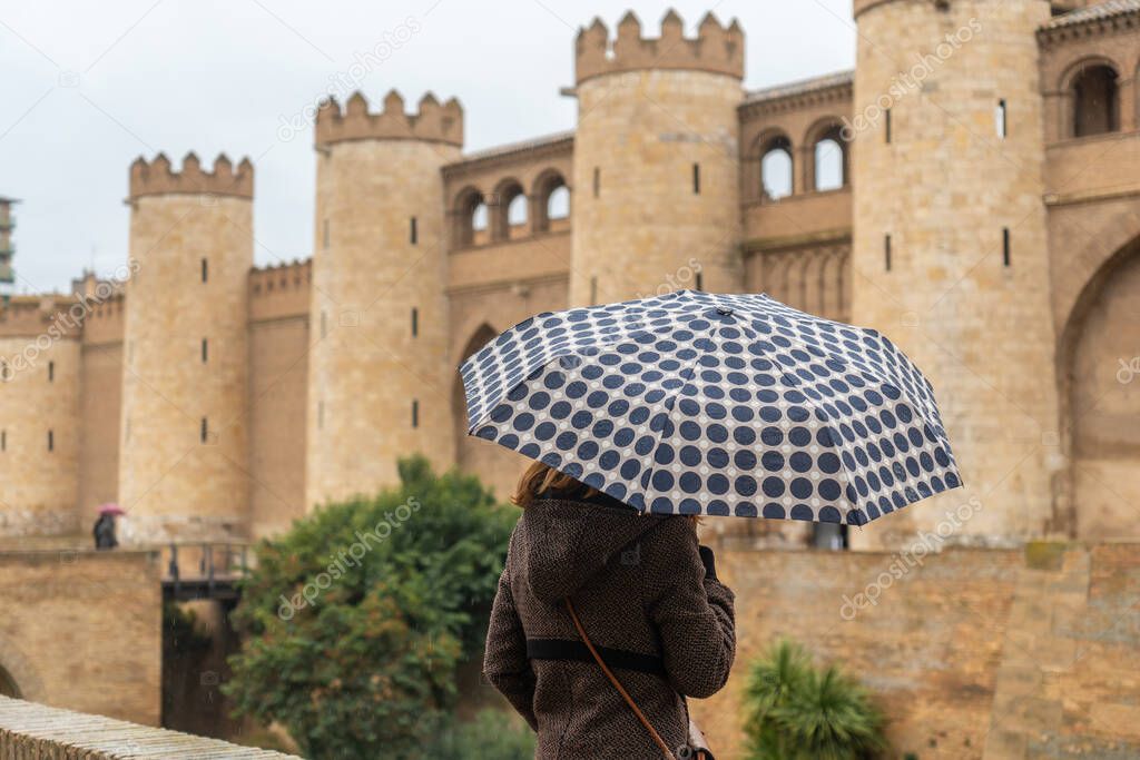 A young woman with an umbrella in the Aljaferia Palace of the Hudie kings of Saraqusta in the city of Zaragoza, next to the Ebro river in Aragon. Spain