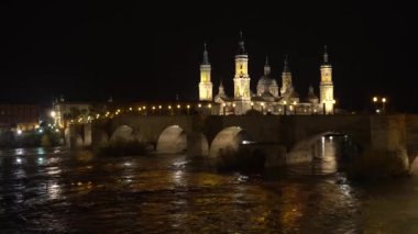 Aragon 'un Zaragoza kentindeki Ebro nehrinin üzerindeki Nuestra Seora del Pilar Bazilikası' nın yanındaki taş köprüden bir gece videosu. İspanya, 4k video