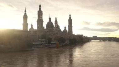 Aragon 'un Zaragoza kentindeki Ebro nehrinin üzerindeki Nuestra Seora del Pilar Bazilikası' nın yanındaki taş köprüden gün batımı. İspanya, 4k video