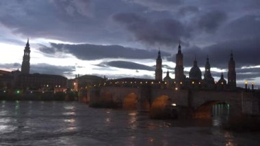Aragon 'un Zaragoza kentindeki Ebro nehri üzerindeki Basilica De Nuestra Senora del Pilar' ın yanındaki Piedra köprüsünde mavi saat. İspanya. Video 4k