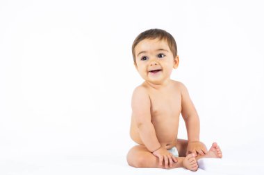 Baby boy in a studio with a white background, newborn caucasian eight months old smiling