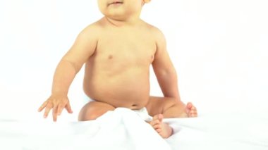 Baby boy in a studio with a white background, newborn caucasian eight months old smiling