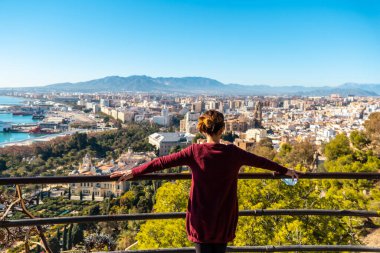 A young tourist looking at the views of the city and the Cathedral of the Incarnation of Malaga from the Gibralfaro Castle in the city of Malaga, Andalusia. Spain