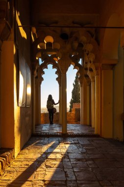 A young woman at sunset from the Arab doors of a courtyard of the Alcazaba in the city of Malaga, Andalusia. Spain. Medieval fortress in arabic style