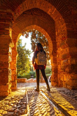 A tourist at sunset at the gate of the Alcazaba wall in the city of Malaga, Andalusia. Spain. Medieval fortress in arabic style