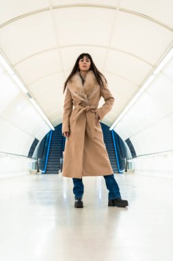 Güzel esmer bir kızın kışın ceketiyle metroya girdiği pozu. Güzel Kafkasyalı tünelde yürüyor