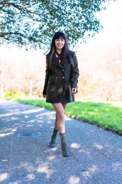 Bahar yaşam tarzı. Parkta yeşil ceketli genç bir kız poz veriyor.