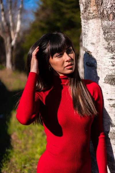 春天的生活方式公园里一位年轻的黑发姑娘的画像 她穿着红色衣服 在一棵树旁休息和欣赏大自然 — 图库照片