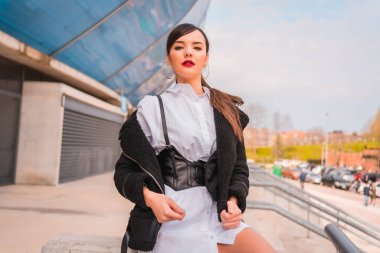 Beyaz gömlekli, siyah deri çizmeli beyaz bir kız. Şehrin tadını çıkarıyorum, Posado. Kameraya bakıyorum.