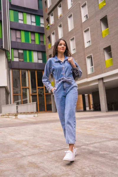 Siyah çantalı, maymun kovboylu, beyaz bir kız. Tatilde şehrin tadını çıkarmak, yeşil bir evde yürüyen genç bir kızın yaşam tarzı, şehir fotoğrafları.