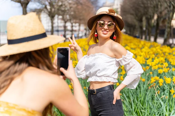 Przyjaciele Wakacjach Mieście Obok Pięknych Żółtych Kwiatów Robienie Zdjęć Telefonem — Zdjęcie stockowe