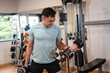 Spor salonundaki sporcu ağırlık çalışıyor.