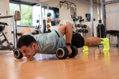 Spor salonundaki sporcu ağırlık çalışıyor.