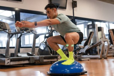 Spor salonunda lastik top üzerinde egzersiz yapan beyaz bir adamın portresi. Sağlıklı ve sağlıklı bir yaşam sürüyor.