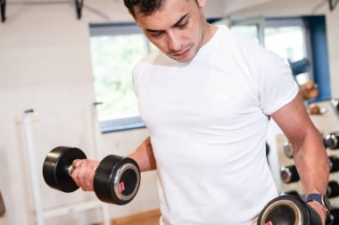 Spor salonundaki sporcu ağırlık kaldırıyor, sağlıklı ve spor yapıyor.