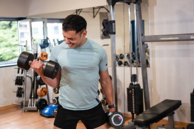 Spor salonunda spor yapan atletik beyaz bir adam ağırlık kaldırıyor, sağlıklı ve sağlıklı bir yaşam sürüyor.