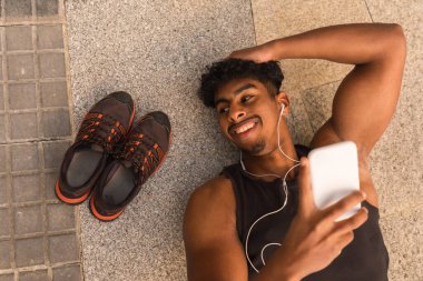 Arap güçlü genç adam şehirde spordan sonra dinleniyor, yerde yatıyor.